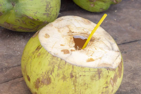 ストロー飲みの準備でココナッツを開きます 新鮮なココの水の写真 木製のテーブルにココナッツの果実 緑のココナッツ カクテル のどが渇いて夏の甘いココナッツ ミルク 市場で天然有機フルーツ — ストック写真