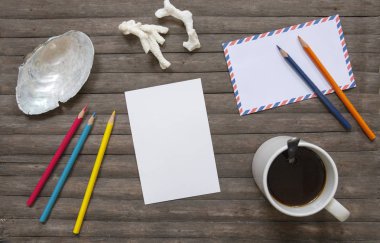 Boş Kartpostal ve kahve düz rustik ahşap zemin üzerinde yatıyordu. Dikey kartpostal mockup. Boş kartı ve kahve fincanı boho zemin üzerinde. Beyaz kağıt levha ve sanat malzemeleri. Renkli hobi afiş şablon