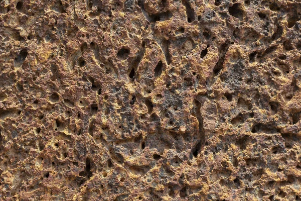 Rusty orange stone texture photo. Winded ancient stone floor background. Weathered rock relief. Old rock surface closeup. Distressed stone texture. Natural floor material. Porous grungy rock formation