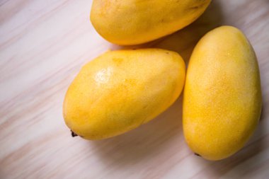 Ahşap zemin üzerine sarı mango. Tropikal meyve demet. Oval sarı mango kazık. Şekerli tatlı veya vejetaryen yiyecekler. Egzotik mango closeup fotoğraf. Lezzetli egzotik meyve mango. Lezzetli sulu meyve