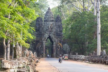 Siem Reap, Kamboçya-26 Mart 2018: Angkor Thom kapısı heykelleri ve motosiklet sürücüleriyle. Khmer mimarisi ile tarihi site. Arkeolojik ilgi yeri. Turist gezileri. Taş oymacılığı