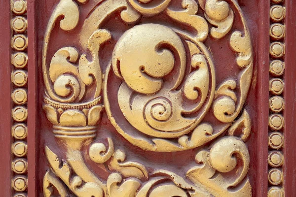 Wooden carved ornament painted in red and golden. Traditional khmer wood carving. Historic place detail. Wooden ornament on buddhist shrine. Sacred temple decoration. Buddhism architecture element