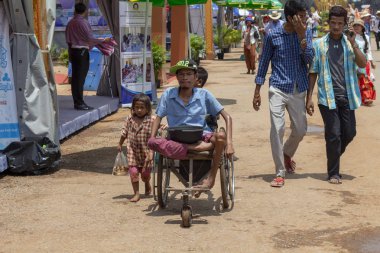 Siem Reap, Kamboçya, 14 Nisan 2018: zavallı çocuk ve halk pazarına sokakta sandalyede Engelli dilenci. Engelli Kamboçyalı dilenci turistik yerde. Asya'da sosyal sorun. Yoksul insanların para istiyorlar