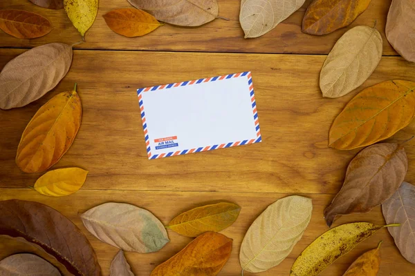 オレンジの葉と木製の背景の空の空気メールの封筒 秋の季節装飾の空封筒 テーブルのモックアップに従来のメール手紙 秋のシーズンのフラット テキストの場所を位置バナー テンプレート — ストック写真