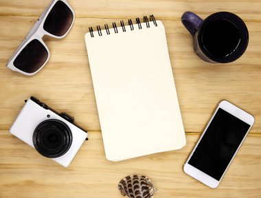 Ahşap masa üzerinde sarmal bir not defteri boş sayfa. Yaz seyahat etmek düz yatıyordu fotoğraf. Tablo üstten görünüm boş sketchbook sayfa. Kağıt defter ve beyaz becerikli alet. Tatil logo veya kroki mockup. Yaz arka plan