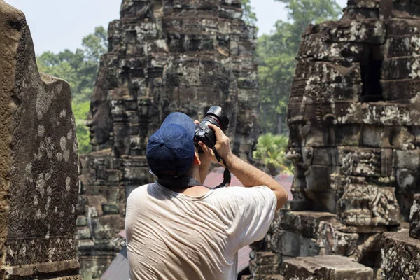 Tourist man making photos in Bayon temple, Angkor Wat. Cambodia travel and sightseeing. Angkor Wat scene. Tourist with professional photo camera. Man shooting ancient ruins. Photographer in Angkor Wat