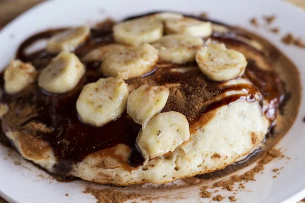 Sweet pancake with banana and chocolate. Banana chocolate dessert flat lay. Sweet kids breakfast. Nutritious food. Delicious dessert closeup. Rich appetite pancake with cacao sauce and tropical fruit