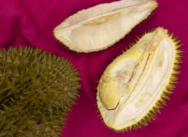 Tropical fruit durian on red background. Whole and cut durian flat lay. Tasty fruit with smell. Exotic fruit durian top view photo. Thailand famous fruit. Tropical garden harvest. Exotic dessert