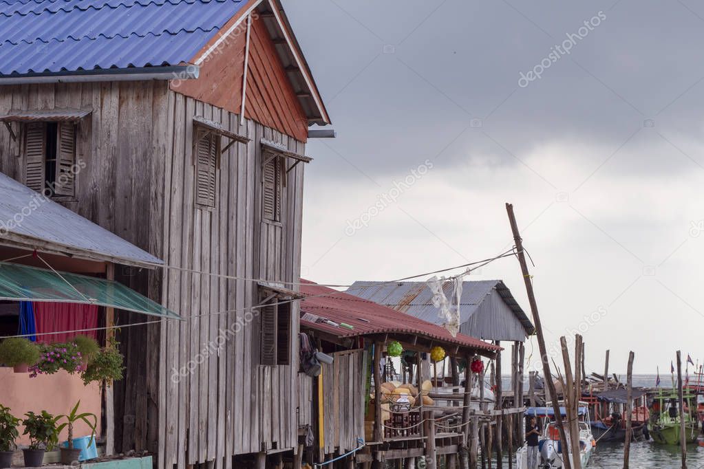 Rustic house on piles in cambodian village. Travel Koh Rong island. Idyllic view of khmer fishermen house and boats. Tropical island lifestyle. Traditional wooden house on pillar standing in sea water
