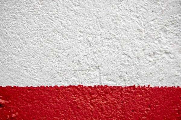 Red and white painted wall photo. Painted brushed texture. Grungy concrete wall closeup. Rustic architecture background. Concrete house wall. Rough painted surface. Vintage or shabby chic backdrop