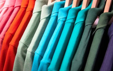 Renkli gömlek üzerinde asılı Satılık Dükkan. Çok renkli polo ahşap askı üzerinde. Yaz mevsimlik giyim mağazası. Unisex Giyim için sıcak hava. Satılık Alışveriş Merkezi. Renk Gradyan t-shirt