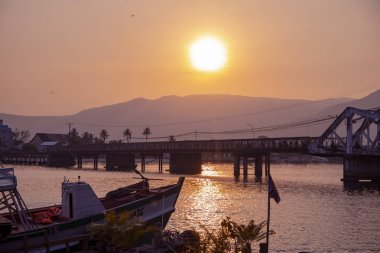 Günbatımı manzara hala Nehri ve uzak dağ. Tropikal ülkede romantik günbatımı. Kentsel köprü ve bay eski gemi ile. Turuncu gökyüzü kentsel peyzaj ile. Kamboçya seyahat fotoğraf