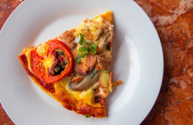 Parça pizza domates, otlar ve peynir beyaz tabakta. Taş masa üstü görünümünde dilim pizza. Ahşap fırın nefis taze pizza. İtalyan mutfağı yemek. Domates Mantarlı peynirli pizza. İtalyan yemeği