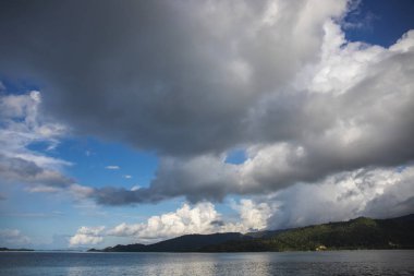 Gri fırtına bulutları ve hala deniz. Tropik ada manzara. Yağmur sezonu cennet. Tayfun bulutlar hala deniz lagün yukarıda. Tropik ada atlamalı. Deniz manzarası ile muhteşem gri bulutlar