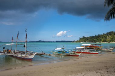 Palawan, Filipinler - 24 Kasım 2018: turkuaz deniz lagün ve tekneler. Güneşli tropik ada manzara. Filippino geleneksel ahşap tekneler. Mavi su ve sarı kum ile pastoral sahil