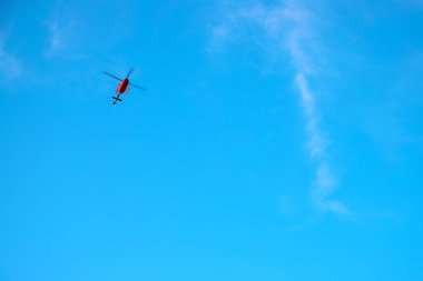 Mavi gökyüzünde kırmızı helikopter. Acil servis helikopter uçuşu. Kırmızı helikopter afişi ve metin yeri şablonu. Sigorta ya da tıbbi destek konsepti. Güneşli mavi gökyüzü ve özel servis uçan aracı