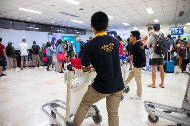 Puerto Princesa, Filipinler - 30 Kasım 2018: Havaalanında tramvaylı turist ve taşıyıcı. Havaalanı servis destek ekibi. Bagaj vagonlu Filipinli çocuk. Güney Asya uluslararası havaalanı.