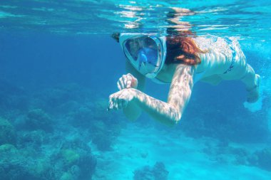 Saçları dökülmüş bir kadın su altında zaman geçiriyor. Tropikal deniz mercan kayalıklarında şnorkelle yüzmek. Dalış maskesi takmış genç bir kız. Mercan resifinin denizaltı fotoğrafı. Aktif deniz tatili. Deniz kenarı etkinliği
