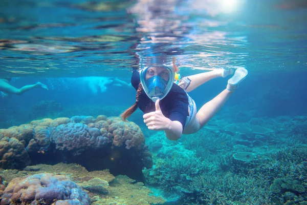 海底をシュノーケリングする若い女性 スノーケルは水中に親指を表示します フルフェイスのシュノーケリングマスクの女性 サンゴ礁の風景の水中写真 熱帯の島で夏休み 海辺のアクティビティ — ストック写真