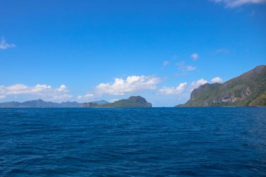 Uzak adalı mavi deniz ve gökyüzü manzarası. Palawan adası deniz manzarası. Filipinler seyahat fotoğrafı. Mavi suyu ve berrak gökyüzü olan güneşli deniz manzarası. Idyllic tropikal deniz kıyısı afişi şablonu