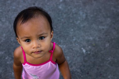 Dumaguete, Filipinler-22 Şubat 2019: küçük kız kamera üst görünüm fotoğraf görünüyor. Gri kentsel arka planda yerli çocuk