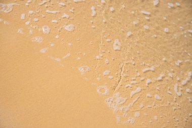 Sarı kum plaj üzerinde köpüklü deniz suyu. Tropikal sahil konsepti fotoğraf. Kum sahilde deniz suyu.