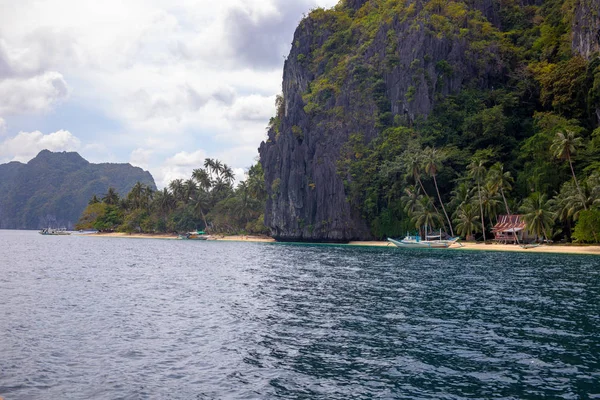 Tropical island in sea. Black cliff and seashore landscape. Philippines island hopping. Green palm trees — Stock Photo, Image