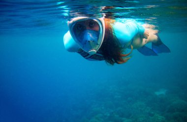 Mavi denizde yüzen bir kadın. Yüzü maskeli bir kız. Şnorkel, sualtı fotoğrafını yakın çekim. Şnorkelli maske.