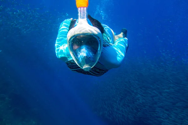 Woman swimming in blue sea. Girl snorkeling in full-face mask. Snorkel with fish school underwater photo — ストック写真