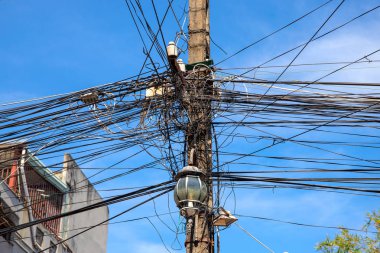 Elektrik kablolarının karışıklığı. Çok fazla bağlantısı olan elektrik direği. Asya elektrik kaynağı. Endüstriyel elektrik direği
