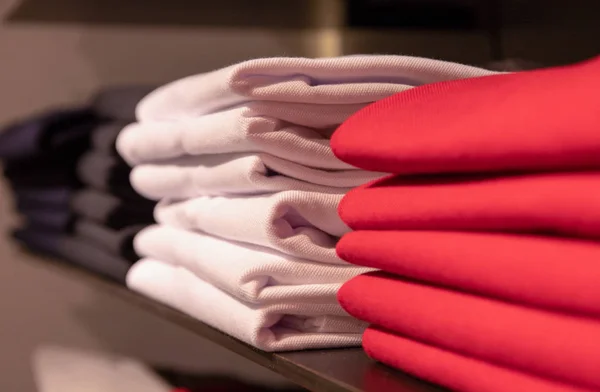 Bílé a červené oblečení na polici. Skládaná košile na prodej. Interiér módní dílny. Klasické barevné variace v každodenním nošení — Stock fotografie