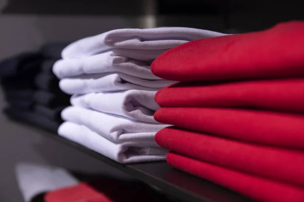 Rot-weiße Männerkleidung im Regal. T-Shirt auf dem Regal zum Verkauf im Geschäft. Herbstliche saisonale Kleidung im Kaufhaus. — Stockfoto