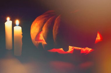 Cadılar Bayramı balkabağı ve mum karanlıkta. Ürkütücü bir klasik fotoğraf. Korkunç yüzlü ve turuncu ışıltılı oyulmuş balkabağı..