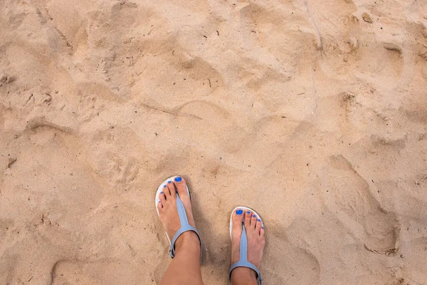 Strand Sand und Frauenfüße von oben gesehen. Mädchenfüße in Sandalen am heißen Sandstrand. Gelber Sand der tropischen Inselküste — Stockfoto