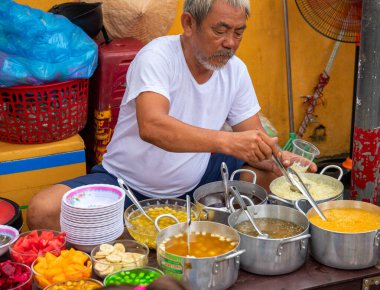 Hoi An, Vietnam - 28 Temmuz 2019: Yiyecek satıcısı ve çorba kasesi olan yerel bir lokanta. Vietnam sokak yemeği. Yaşlı adam çorba yapıyor.