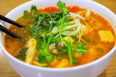 Et suyuna çorba, sebze ve çubuklu beyaz seramik kasede yeşillik. Geleneksel Vietnam mutfağı