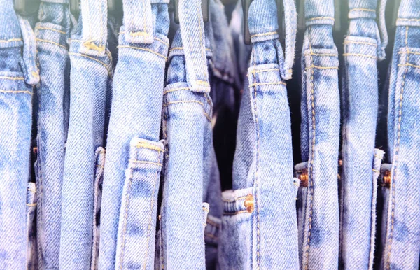 Blue Jeans size row in warderobe or on store hanger. Faded jeans retro style photo. Vintage wear on hanger in store.