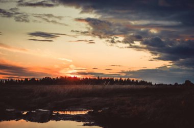 Ateşli gün batımı bir su birikintisi yansıyan