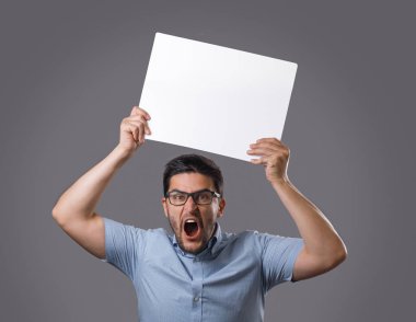 Beyaz boş poster başının üzerinde tutan genç deli brunet adam. Gereksinimleri ve talepleri olan insanlar. Gösteri insanları