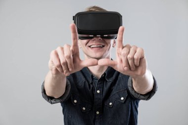 İnsan sanal gerçeklik gözlükleri kullanmak ve gri arka plan üzerinde çerçeve