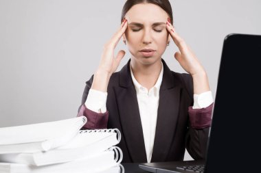 Genç iş kadını çalışma kağıtları ve Kitaplar ile laptop ile masaya oturan duraklama alarak yorgun. Ofiste zor iş akışı