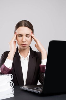 Genç iş kadını çalışma kağıtları ve Kitaplar ile laptop ile masaya oturan duraklama alarak yorgun. Ofiste zor iş akışı