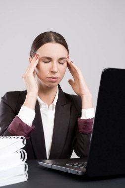 Genç iş kadını çalışma kağıtları ve Kitaplar ile laptop ile masaya oturan duraklama alarak yorgun. Ofiste zor iş akışı