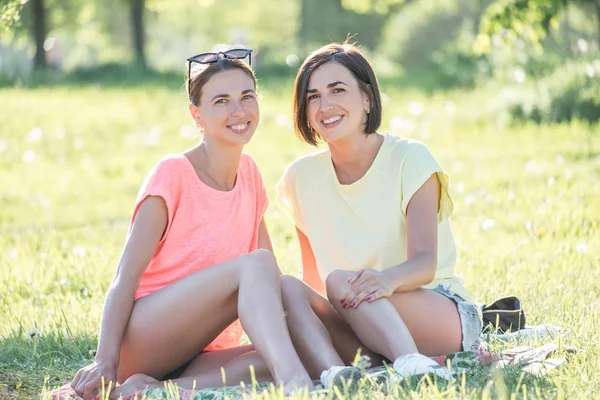 Retrato Livre Duas Garotas Alegres Sentadas Gramado Divertindo Juntas Parque — Fotografia de Stock