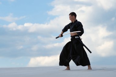 Geleneksel giysiler içinde konsantre adam Japon savaş sanatı - bir Japon kılıç ile çölde iaido - sunset akşam gökyüzü arka plan üzerinde sırasında bir katana pratiği yapıyor. Yan görünüm.
