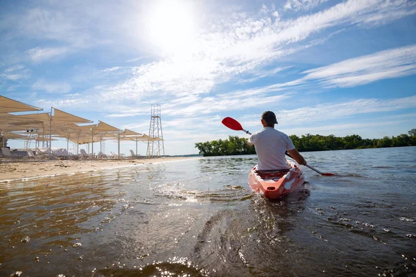 Bir güneşli sabah - su sporları tesisi üzerinde denizin plajın yanında bir kayık kürek çekmeye dostum. Arkadan görünüm, arka ışık, geniş açı.