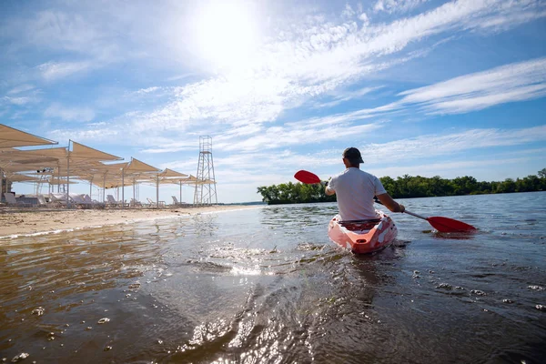 Bir güneşli sabah - su sporları tesisi üzerinde denizin plajın yanında bir kayık kürek çekmeye dostum. Arkadan görünüm, arka ışık, geniş açı.
