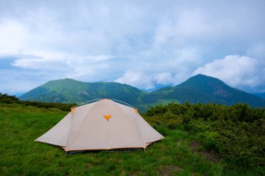 Yeşil dağ çayır ormanlık tepeler hangi ufuk - önce dağlarda düşük ağır bulutlar altında uzanan fırtına arka plan üzerinde çadır. Geniş açı.