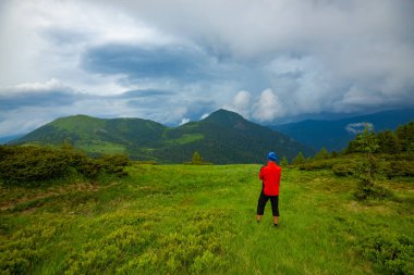 Maceracı yeşil çayır on ormanlık tepeler Panoraması hayran hangi ufuk düşük ağır bulutlar altında uzanan duruyor. Arkadan görünüm, geniş açı.
