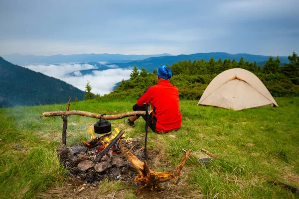 Adventurer Sits Camp Next Bonfire Green Meadow Admires Mountain Ranges — Stock Photo, Image